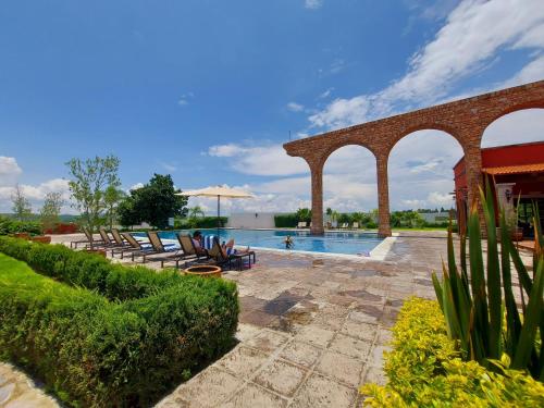 a pool at a resort with chairs and umbrellas at Casa Kora by Avelia in San Miguel de Allende