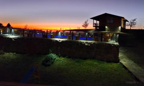 a sunset over a stone wall with a building at Complejo Apus in La Cumbrecita