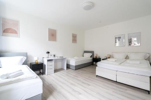 a white room with two beds and a desk at Leoben Comfort Lodge Anytime Check In for Business and Family in Leoben