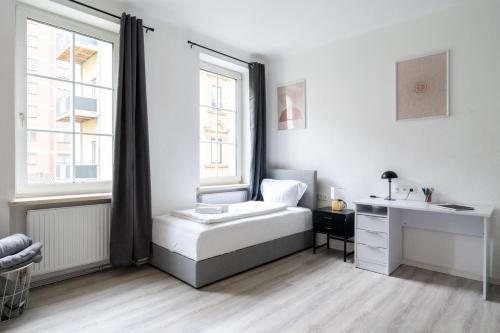 a white bedroom with a bed and a desk at Leoben Comfort Lodge Anytime Check In for Business and Family in Leoben