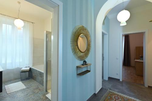 Villa Gloriette - BoutiqueAppartements am Wörthersee في بويرشاك آم فورثيرسي: حمام مع مرآة على الجدار الأزرق