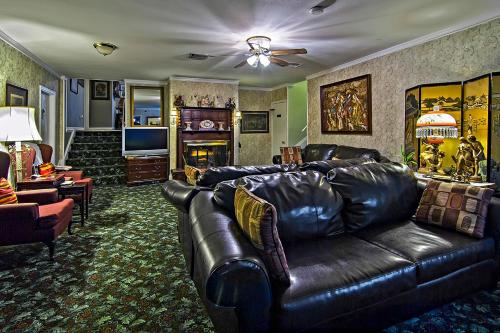 a living room with a leather couch and a television at Rose Manor Bed & Breakfast in New Orleans