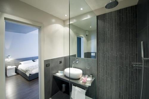 a bathroom with a sink and a mirror and a bed at Piccolo Hotel in Malcesine