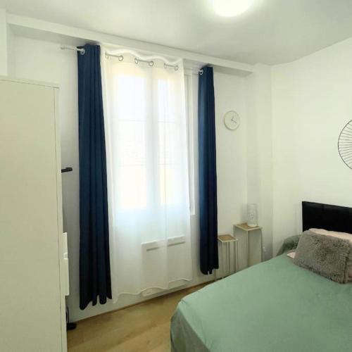 - une chambre avec un lit doté de rideaux bleus et d'une fenêtre dans l'établissement Charmant Appartement F2 - Paris 13ème, à Paris