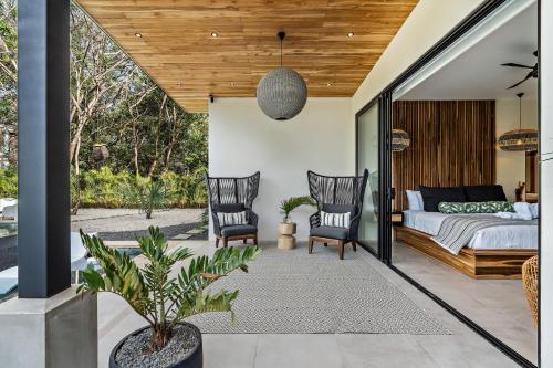 a bedroom with a bed and two chairs at Casa Ola Aloha in Playa Avellana