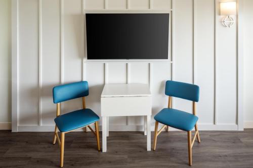 two chairs and a white table with a tv on a wall at Harbor Hotel Provincetown in Provincetown
