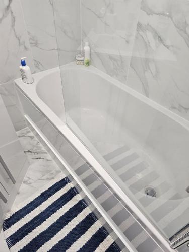 a white tub in a bathroom with a blue and white rug at WOREM HOUSe-2 FOR 1 in Manchester
