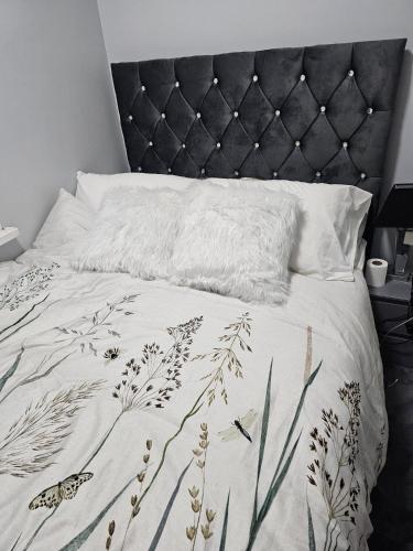 a bed with a black headboard and a white blanket at WOREM HOUSe-2 FOR 1 in Manchester