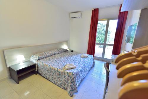 a bedroom with a bed and a table and a window at Eden Park Hotel in Marina di Campo