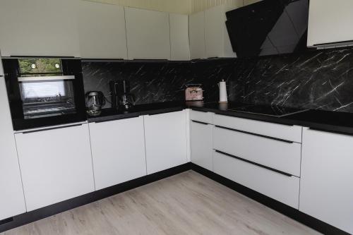 a kitchen with white cabinets and a black counter top at Anil‘s Ferienhaus in Olsberg