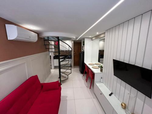 a living room with a red couch and a kitchen at Flat 502 com piscina privativa - 02 quartos in João Pessoa