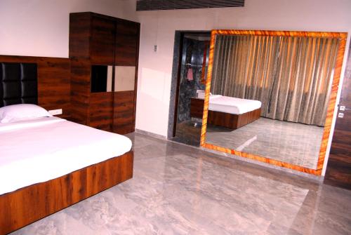 a bedroom with two beds and a mirror at Hotel Apaar in Diu