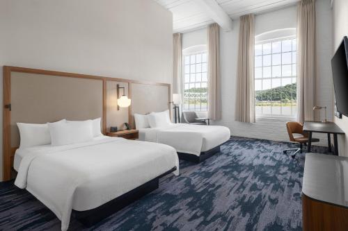 a hotel room with two beds and a flat screen tv at Fairfield Inn & Suites Madison Historic Eagle Cotton Mill in Madison