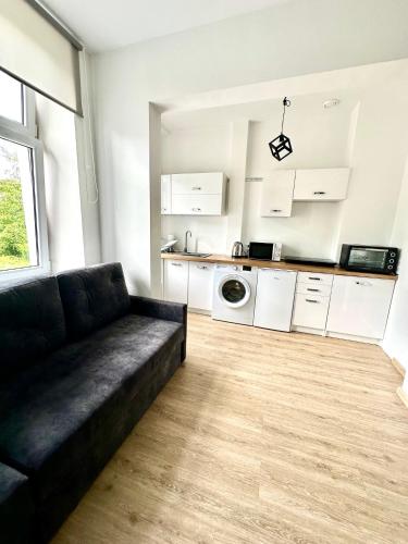 a living room with a couch and a kitchen at Apartament Rodzinny L7 in Kalisz