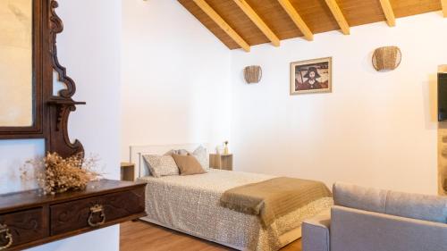 a bedroom with a bed and a couch at Casa da Igreja by Casas do Planalto in Adeganha