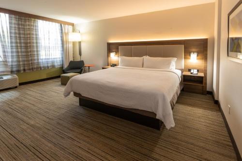 a hotel room with a large bed and a chair at Holiday Inn Express - Grand Island by IHG in Niagara Falls