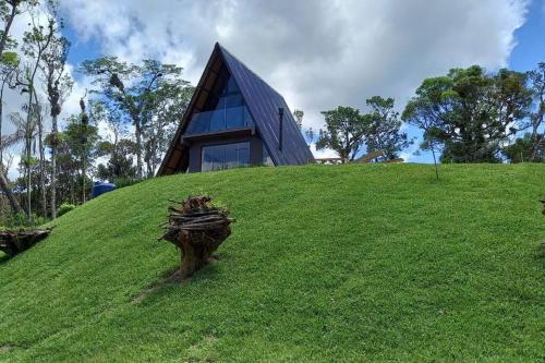 a house on top of a grassy hill at Chalé dos Encantos - Antônio Carlos in Antônio Carlos
