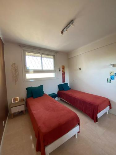 - une chambre avec 2 lits avec des draps rouges et une fenêtre dans l'établissement 3 Pièces Vue mer & Iles de Lérins, à Cannes