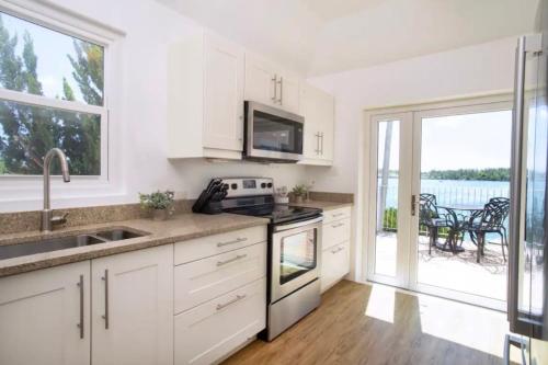 a kitchen with white cabinets and a view of a patio at Modern Apartment St Georges Bermuda in Saint George