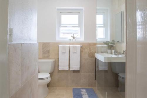 a bathroom with a toilet and a sink and a window at Modern Apartment St Georges Bermuda in Saint George
