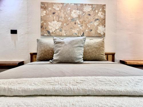 a bed with pillows and a painting on the wall at Chilamate Holiday House in Puerto Viejo