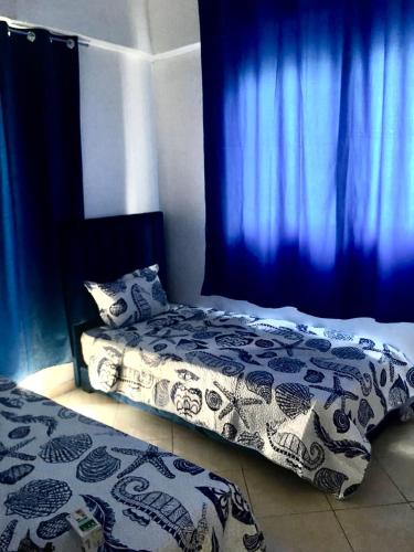 a bedroom with a bed with blue curtains at Mohammed V Airport Appartement in Deroua