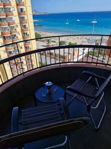 a table and chairs on a balcony with a view of the beach at Torres del Sol 11th floor Atlantic view - Las Americas in Playa de las Americas