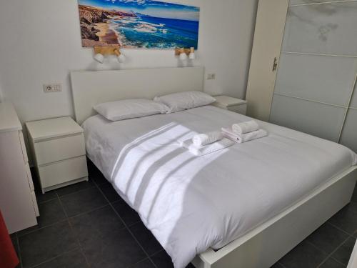 a bedroom with a white bed with towels on it at Torres del Sol 11th floor Atlantic view - Las Americas in Playa de las Americas
