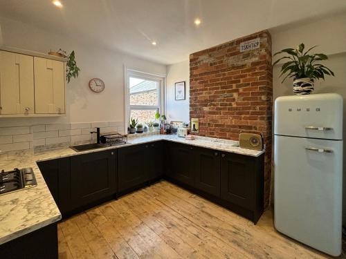 a kitchen with a white refrigerator and a brick wall at Charming Edwardian maisonette in trendy location, minutes from restaurants and pubs in Ashley Cross, Poole in Poole