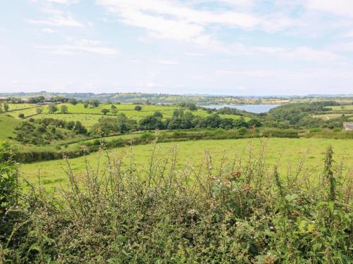 a view of a green field with trees and a lake at The Ivy Barn in Hognaston