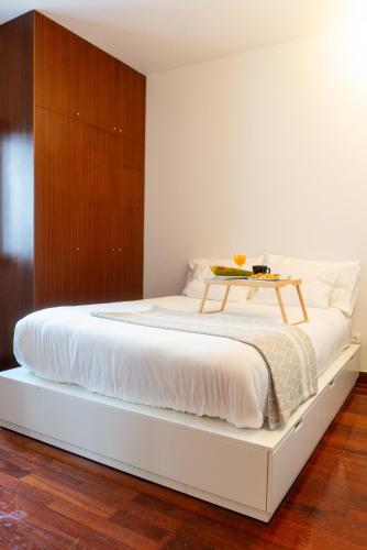 a bedroom with a white bed with a wooden cabinet at Seaside Cozy Apartment with private Terrace in Porto