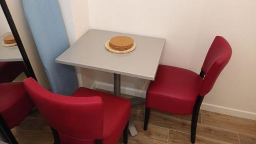 une table avec deux chaises rouges et un chapeau dans l'établissement bel appartement proche stade de France, à Paris