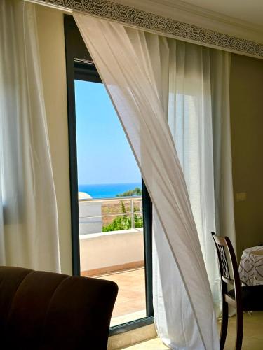 a room with a window with a view of the ocean at Asilah Prestige -Vue Mer -Haut Standing - Piscines- Plage à 5 minute - Garage privée - Navette in Asilah