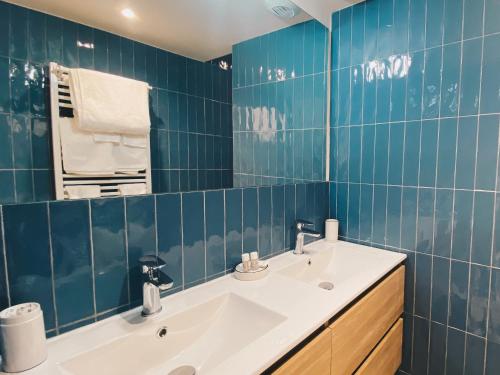 La salle de bains est pourvue de carrelage bleu, d'un lavabo et d'un miroir. dans l'établissement Villa avec piscine à Carnon Plage à 20m de la plage idéale pour 8 à 10 personnes, à Mauguio