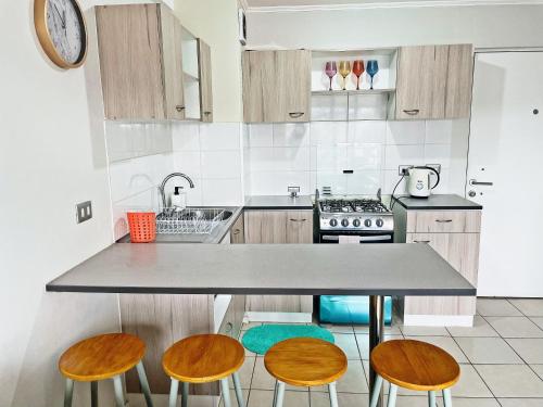 a kitchen with a counter and four stools at Departamento céntrico, acogedor y bien equipado in Concepción