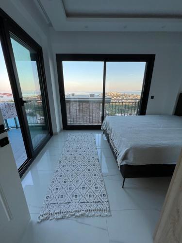 a bedroom with a bed and large windows at Villa Yakışıklı Bodrum vue mer avec piscine privée in Milas