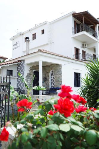 a white building with red flowers in front of it at Hotel Defkalion in Álli Meriá