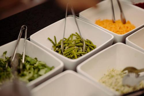 a group of white dishes filled with vegetables and rice at Das gemütliche Dorfhotel Kaltenhauser in Hollersbach im Pinzgau
