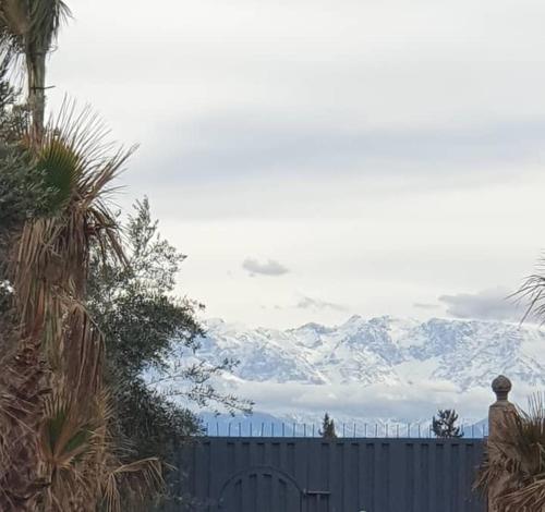 a snow covered mountain in the distance behind a fence at Ferme ADAM Agafay Marrakech in Marrakech