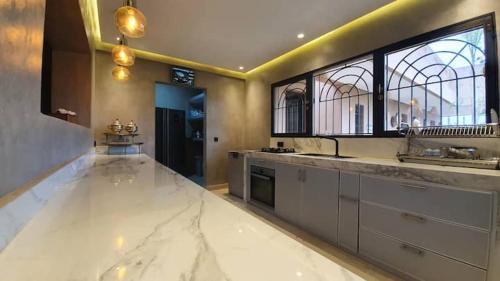 a large kitchen with white marble counter tops and windows at Ferme ADAM Agafay Marrakech in Marrakech