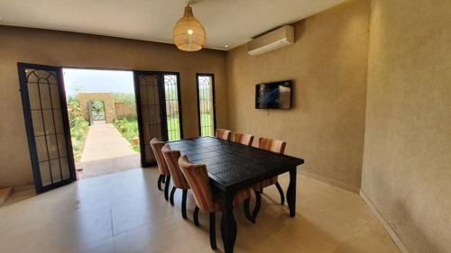 a dining room with a black table and chairs at Ferme ADAM Agafay Marrakech in Marrakech
