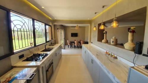a large kitchen with a stove and a dining room at Ferme ADAM Agafay Marrakech in Marrakech