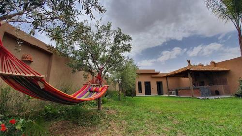a red hammock in a yard next to a house at Ferme ADAM Agafay Marrakech in Marrakech