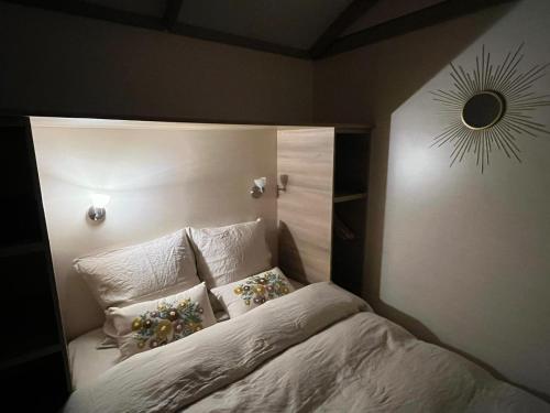 - un lit avec des oreillers et un miroir mural dans l'établissement ROULOTTE AU COEUR DES ANIMAUX - Ecodomaine Rêver Ailleurs, à Champfrémont