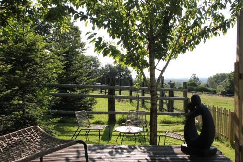 un patio avec des chaises, une table et un arbre dans l'établissement ROULOTTE AU COEUR DES ANIMAUX - Ecodomaine Rêver Ailleurs, à Champfrémont