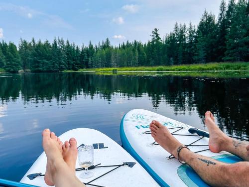 two people are sitting on their boards on a lake at Le Willow Exitchalets Lake, Billard & Spa in Val-David