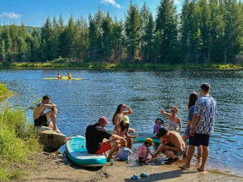a group of people sitting on the shore of a lake at Le Willow Exitchalets Lake, Billard & Spa in Val-David