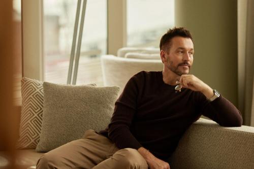 a man is sitting on a couch at The Tasman, a Luxury Collection Hotel, Hobart in Hobart