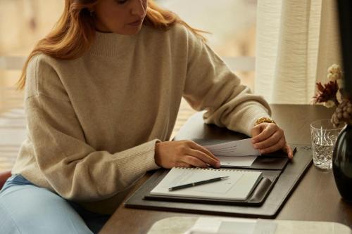 a woman sitting at a table with a laptop computer at The Tasman, a Luxury Collection Hotel, Hobart in Hobart