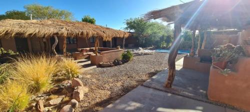 a house with a straw roof and a yard at Hotel Pat'ta Hoiri in San Pedro de Atacama